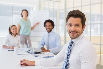 Obraz premium Smiling businessman with colleagues in meeting at office