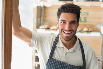 Smiling confident male barista at coffee shop