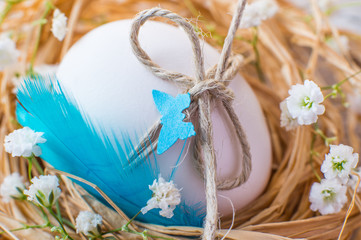 Easter rustic decorated egg in nest and spring flowers.