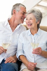 Senior couple sitting on couch drinking white wine