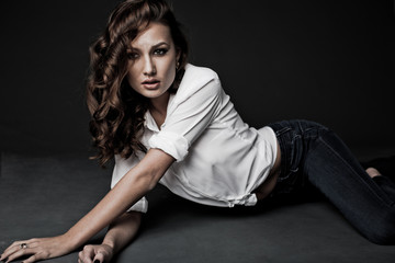 Lovely woman in white blouse and blue jeans lying on the floor