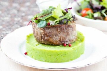 Grilled beef steak, green mashed potatoes with peas, herbs
