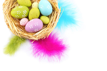 Easter eggs in bowl and decorative feathers isolated on white