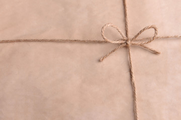 String tied in  bow on beige paper packaging close-up