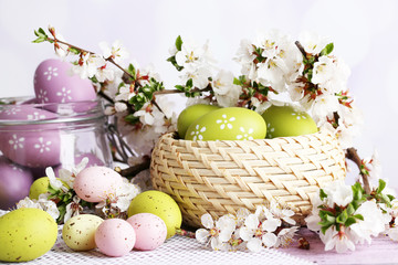 Composition with Easter eggs in glass jar and wicker basket,