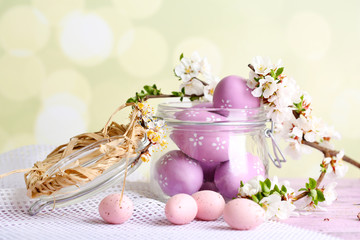 Composition with Easter eggs in glass jar and blooming branches