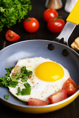 Scrambled eggs and bacon on frying pan on table close-up