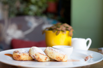 Cheese pancakes with sour cream on a white plate. Breakfast