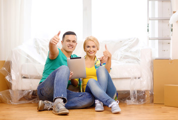 smiling couple with tablet pc in new home