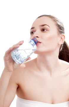 Young woman drinking mineral water bottle, isolated on white