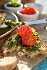A piece of bruschetta with tomato and herb pesto