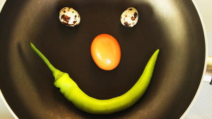 smiley food,  two quail eggs a chicken egg and pepper  in a pan