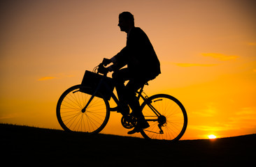 Fototapeta na wymiar Businessman riding bicycle on the hill