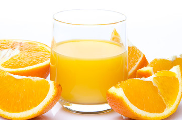 A glass of orange juice with orange quarters