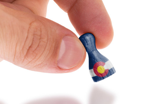Hand holding wooden pawn, flag painting, selective focus