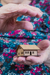 wrinkled hands holding a small house