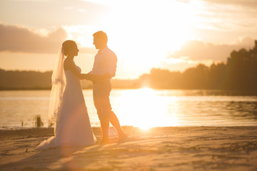 Fototapeta premium Newly married couple on the river with sunset