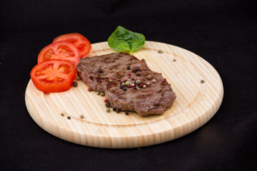 Steak auf einem Holzteller mit Tomaten und Weißbrot