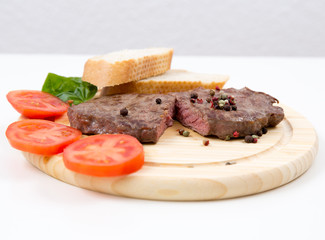 Steak auf einem Holzteller mit Tomaten und Weißbrot