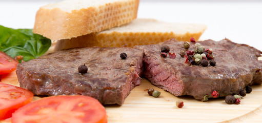 Steak auf einem Holzteller mit Tomaten und Weißbrot