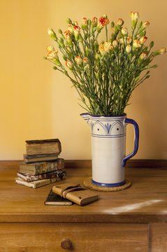 carnation flowers bouquet in vase with books on table