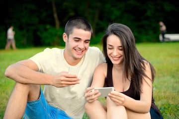 Beautiful young couple browsing smart phones and laughing