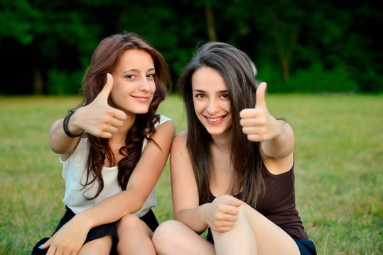 Two beautiful young women giving thumbs up sign and smiling