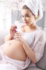 Piękna kobieta w ciąży maluje paznokcie - obrazy, fototapety, plakaty