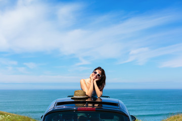 Woman on summer travel leaning out sunroof