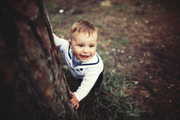 baby hiding behind tree in park