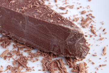 Big chunk of milk chocolate and shavings on white plate