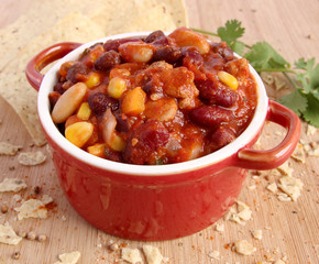 Chili con carne in red bowl with nacho chips and spice