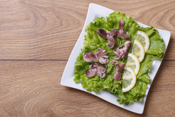 small octopus with lemon slices on lettuce. top view.