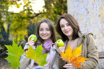 Two young women holding green apples and smiling