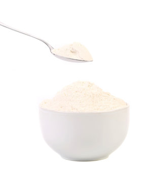 Spoon and white bowl with flour.