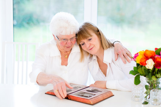 Beautiful woman and her loving mother watching photo album