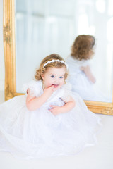 Fototapeta na wymiar Adorable toddler girl in a beautiful white dress