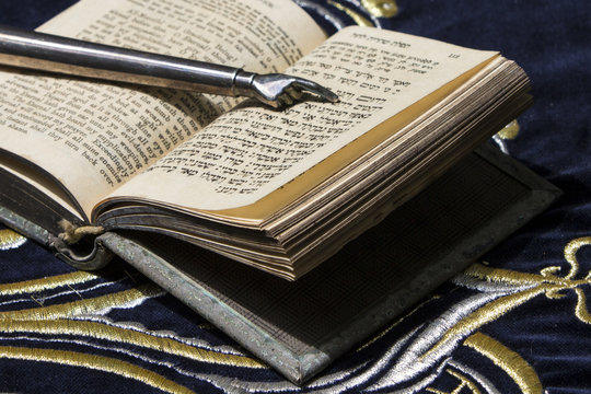 Open bible book in Hebrew with silver pointing hand