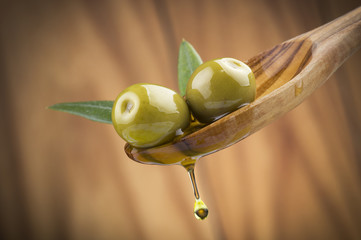 Two olives and leaves with drop oil on wood spoon - 63635489