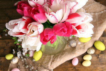 Fototapeta na wymiar Composition with Easter eggs and beautiful tulips in glass jug