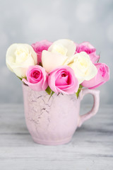 Beautiful roses in cup on light background