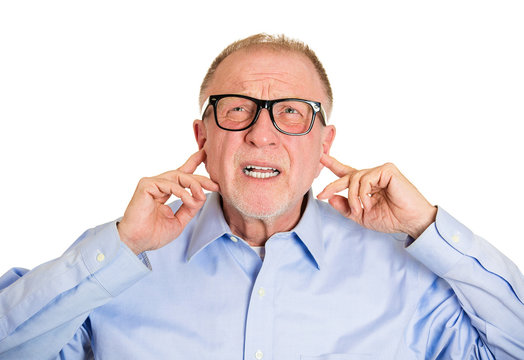 Loud noises. Annoyed old man covers his ears, tired of neighbor
