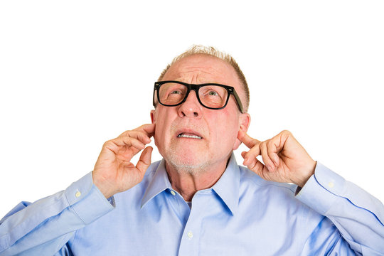 Loud noises. Annoyed old man covers his ears, tired of neighbor