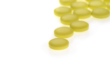 Stack of yellow pills on white background