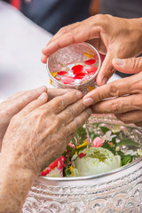 Pour water on the hands of revered elders and gives blessing in
