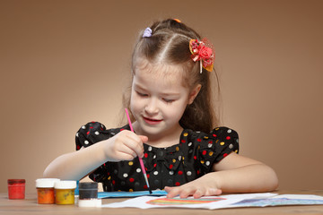 Little girl draws paints in kindergarten