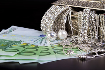 Silver jewelry and Euro on black background