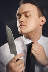 Portret  młodego człowieka przeglądającego się w ostrzu noża. - obrazy, fototapety, plakaty