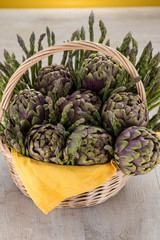 Obraz premium Cestino di vimini con carciofi ed asparagi su un tavolo