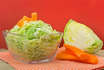 Bowl of green cabbage salad decorated with carrot.